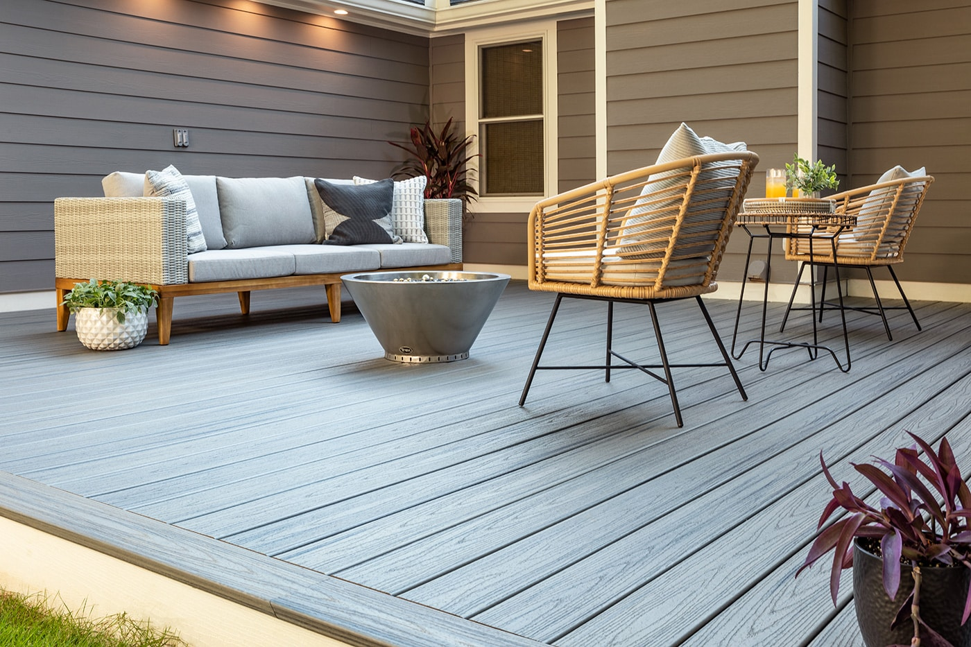 Grey composite deck with a modern fire bowl, wicker chairs and low-maintenance railing