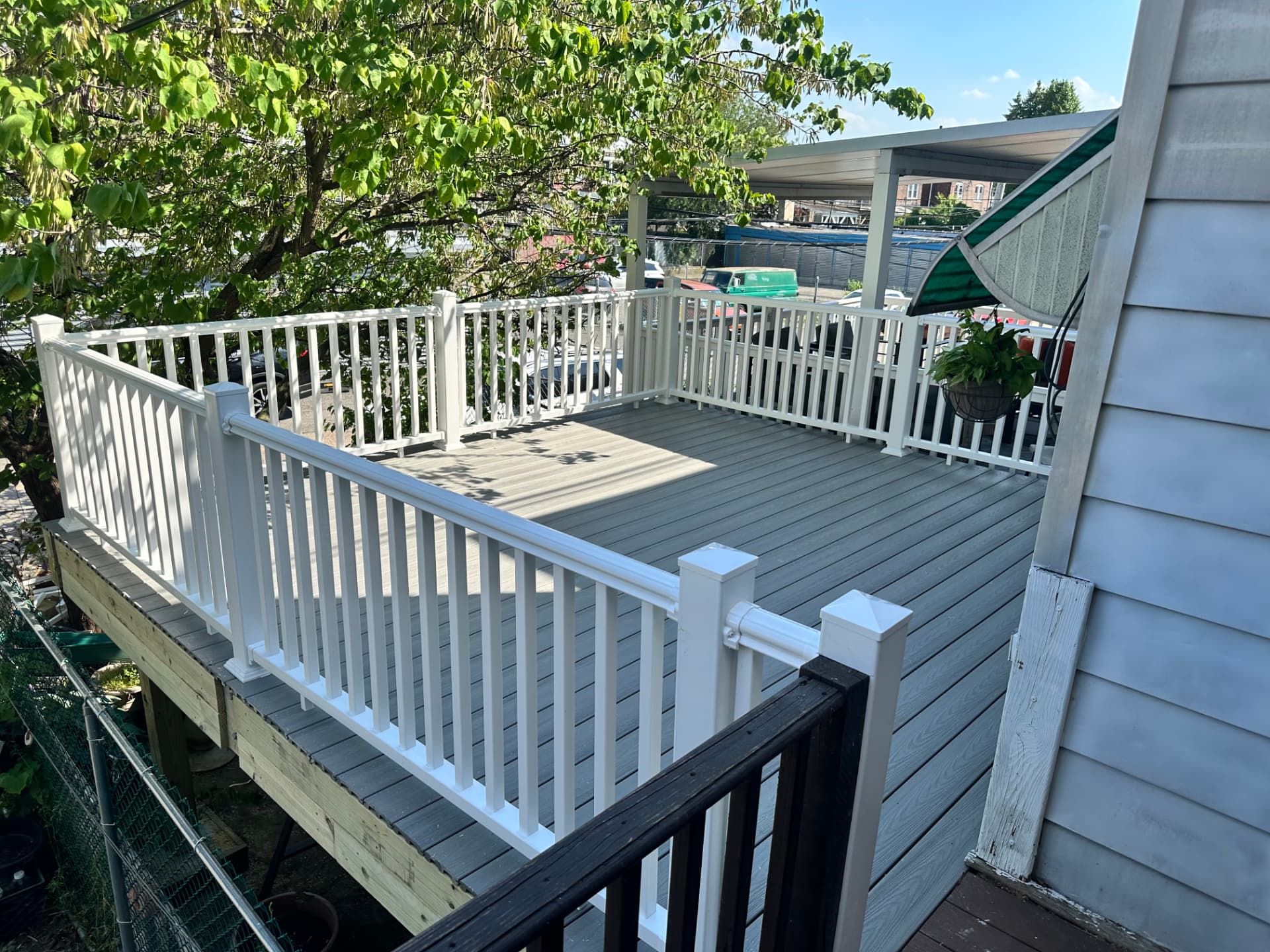 Grey composite deck with white vinyl railing and stairs in a city backyard