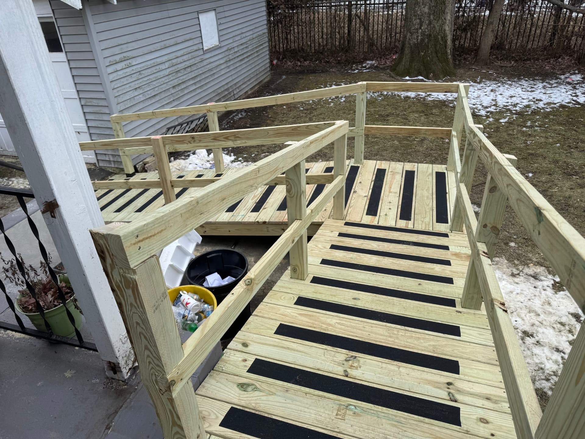 Pressure-treated deck landing and steps with black non-slip strips and railing