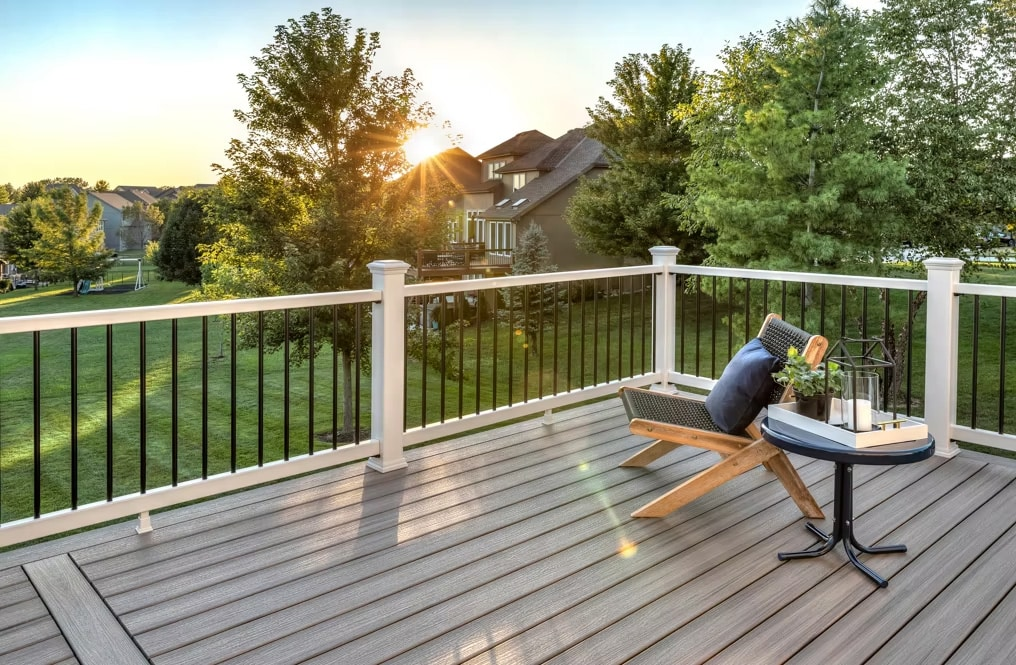 Warm composite deck at sunset with a lounge chair overlooking a green backyard